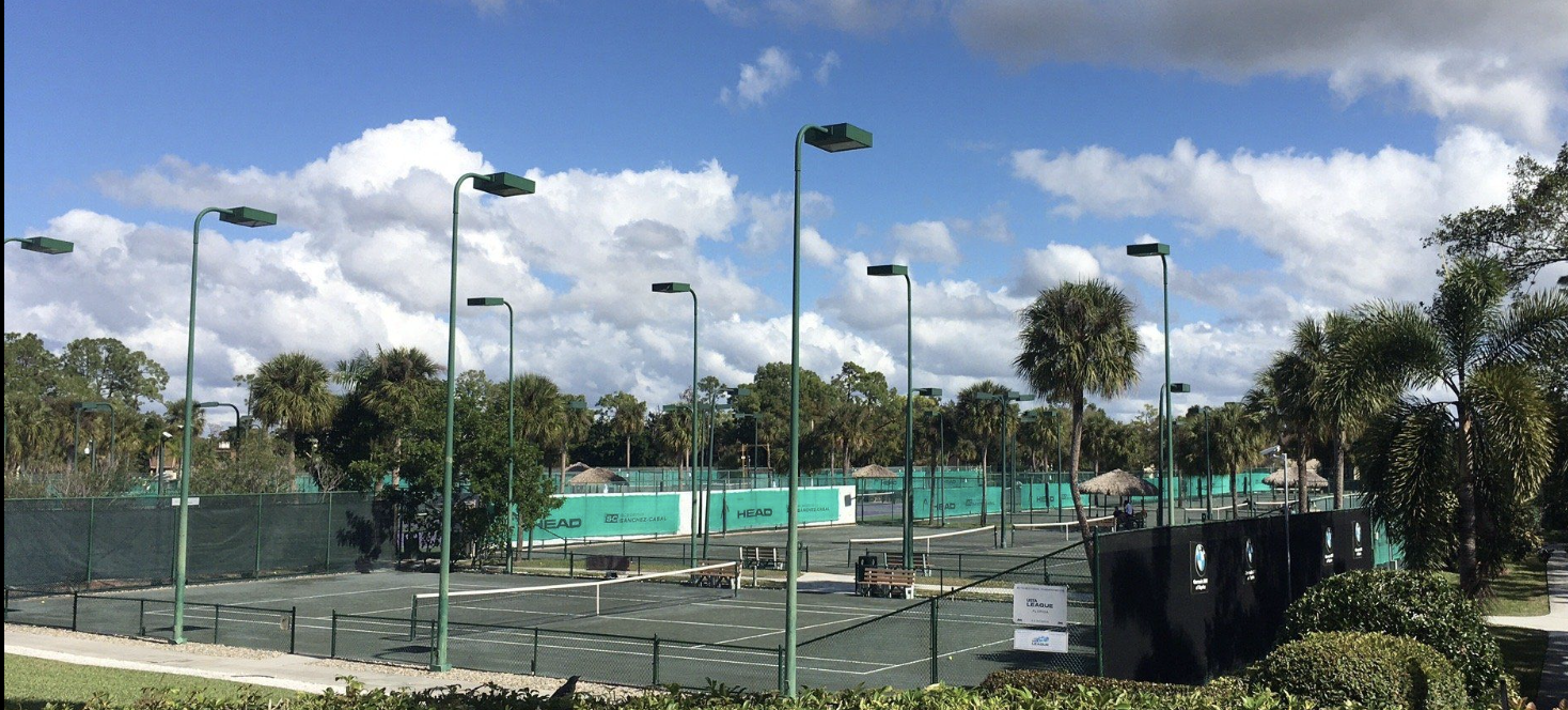 Tennis courts with lighted play areas surrounded by palm trees and tropical landscaping, part of this property's recreational amenities.
