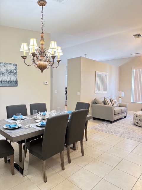 Gather around your elegant dining table beneath the warm chandelier, then unwind in your cozy living space.