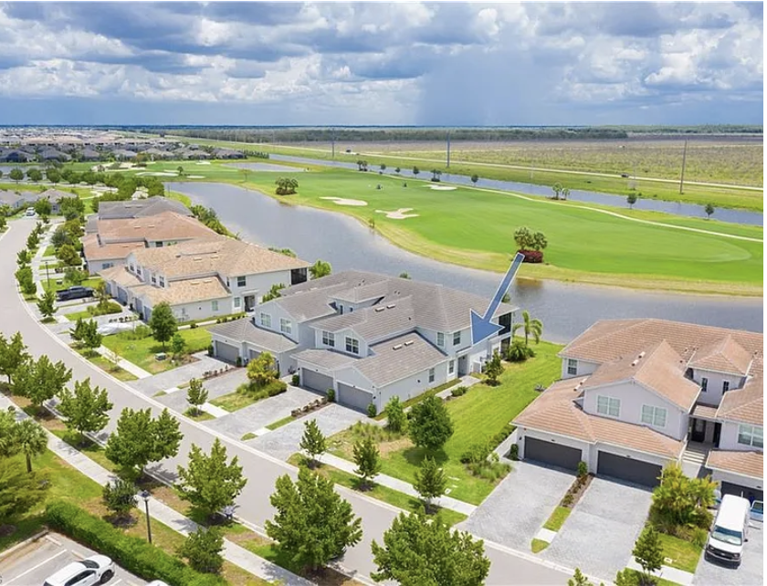 Aerial view of the rental home situated in a peaceful golf course community, with lush greens and waterways framing the neighborhood.