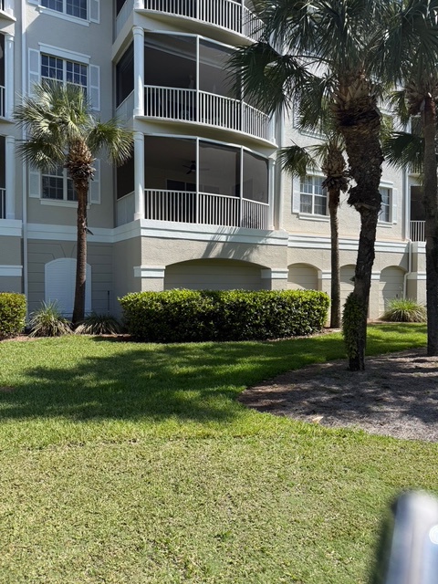 Coastal vacation property featuring screened balconies, tropical palm trees, and manicured landscaping.