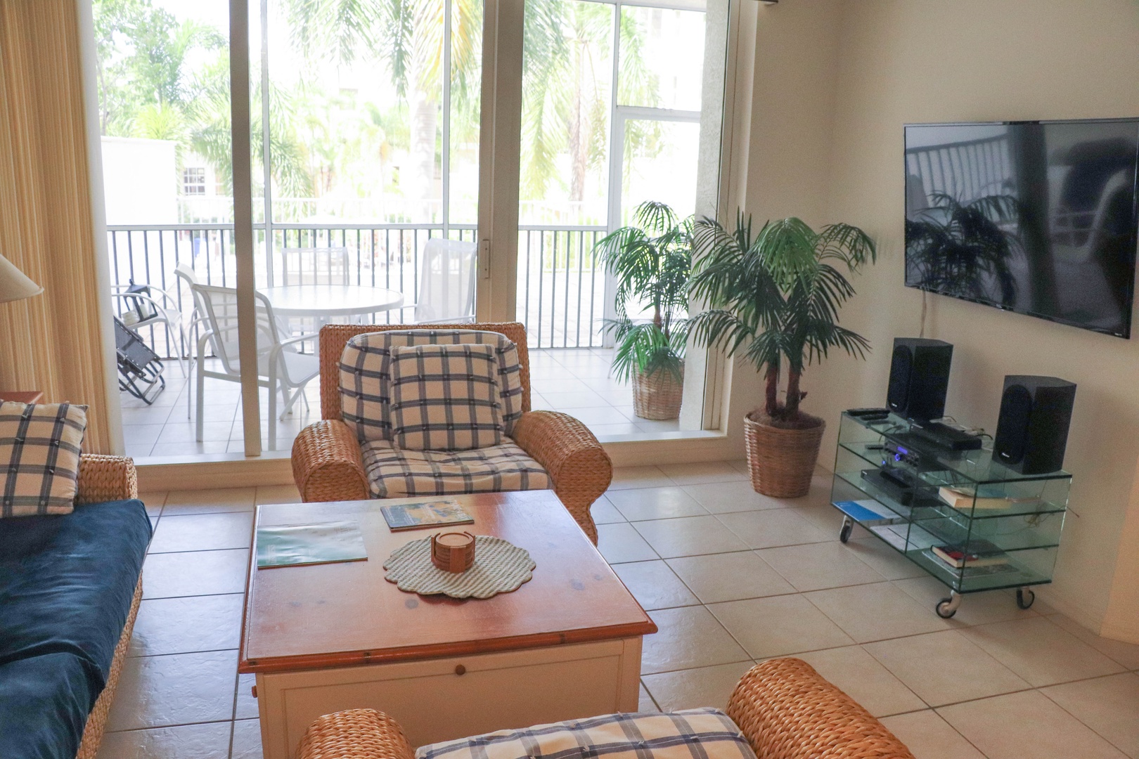 Unwind in your bright living room with tropical garden views and comfortable wicker seating perfect for morning coffee.