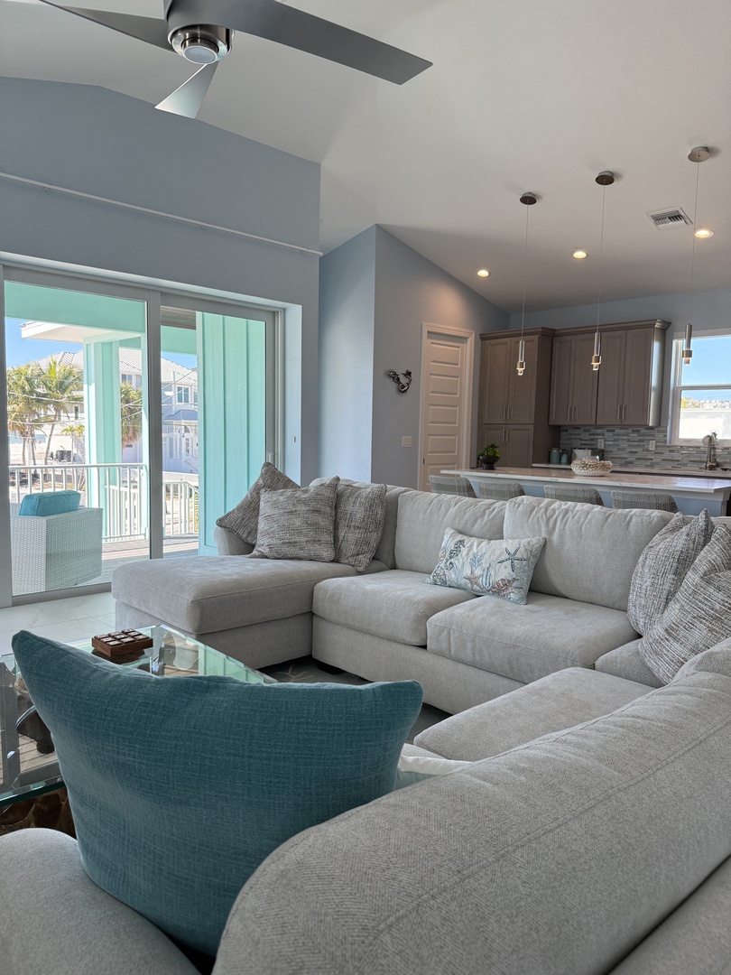 Sink into plush gray sofas in your bright living space, where soft lighting and pool views create the perfect retreat for relaxation.