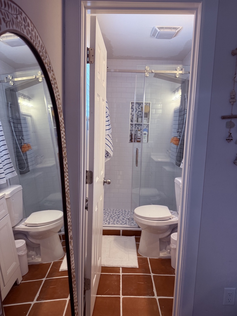 Step into your private bathroom with crisp white tiles, a refreshing shower, and fresh towels waiting for you after a day of exploring.
