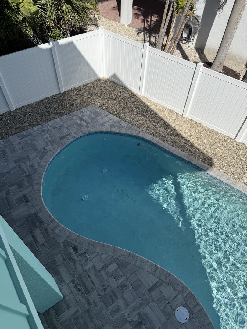 Aerial view of the property's sparkling swimming pool surrounded by stone decking and modern outdoor lounging areas.