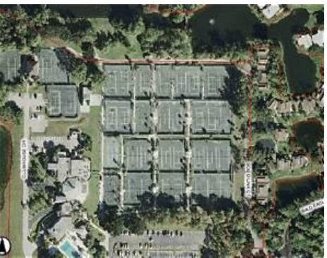 An aerial view captures the property's layout within the surrounding neighborhood, showing residential buildings, tennis courts, waterways, and lush greenery throughout the area.