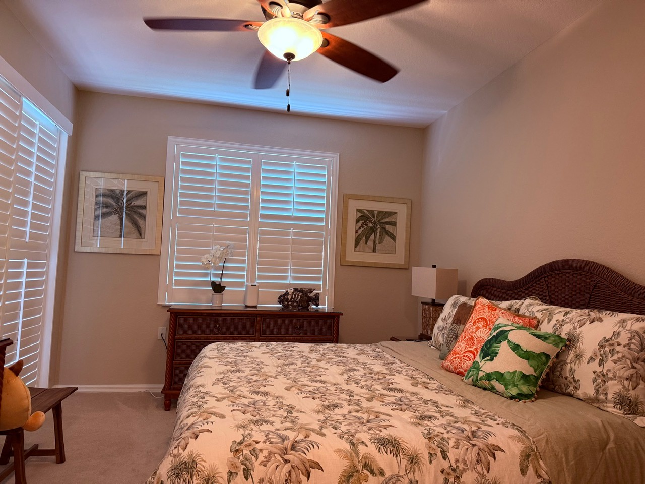 Bedroom 1 King bed. Sink into the plush bed surrounded by tropical touches and soft natural light—your peaceful retreat awaits beneath a gently whirring ceiling fan.