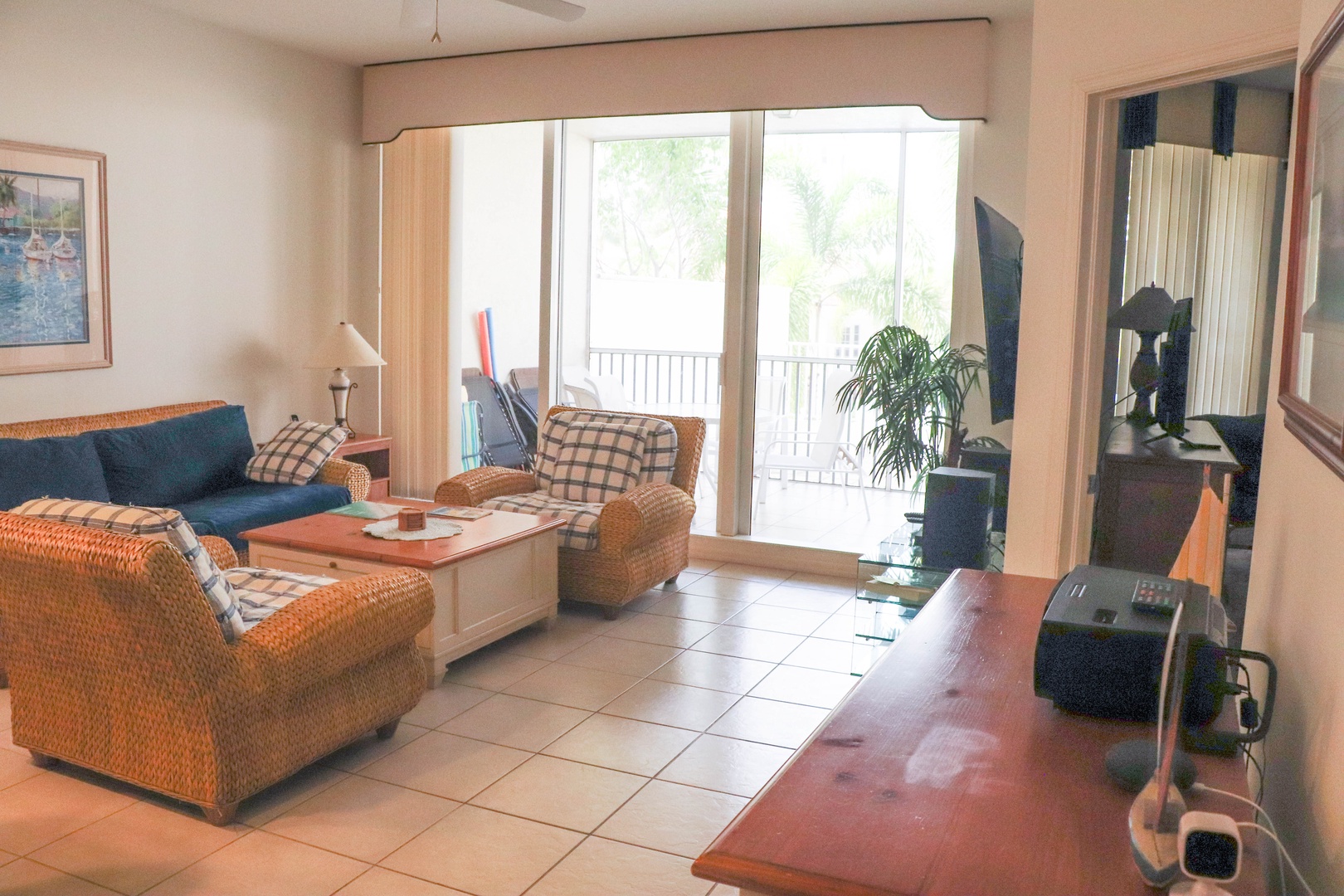 Relax in your comfortable living space with wicker seating, natural light streaming through sliding doors, and your own private balcony beckoning outside.