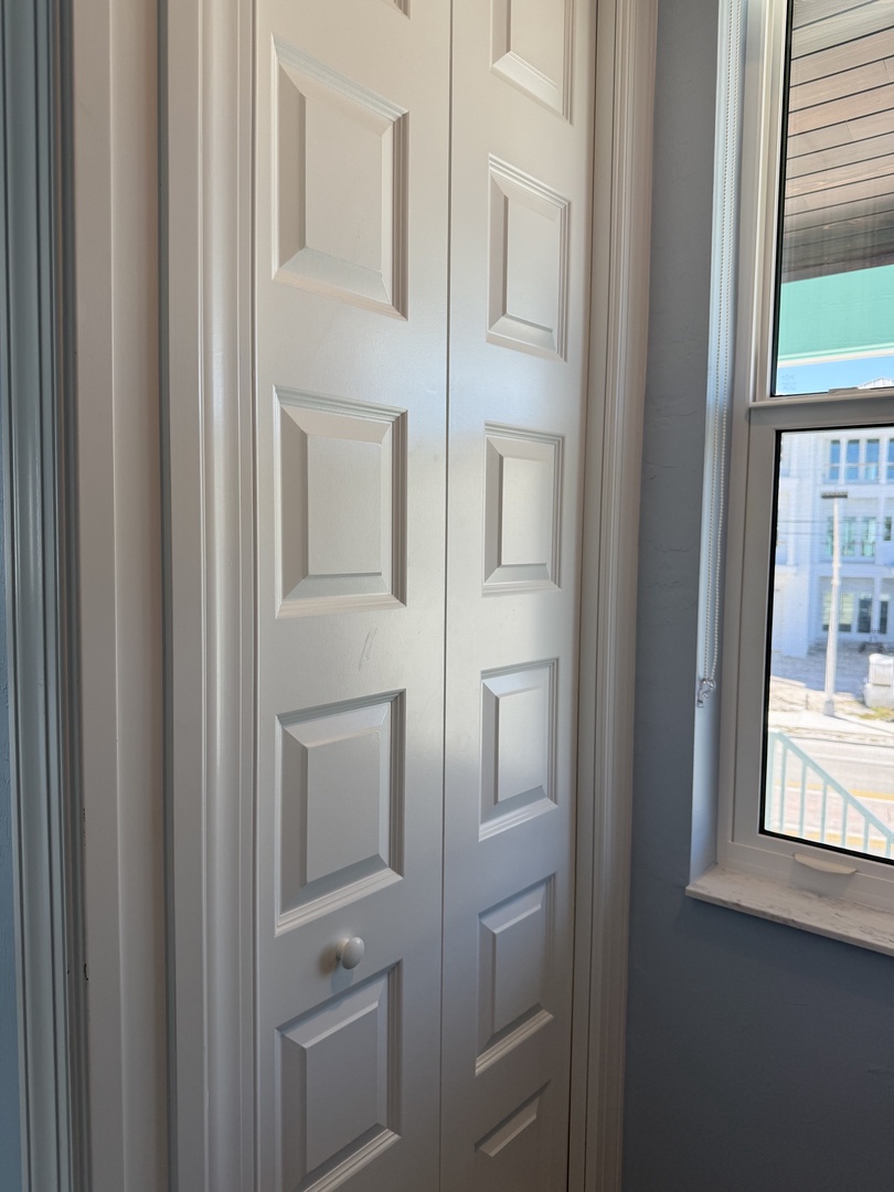 Store your belongings in style with elegant built-in storage featuring classic paneled design beneath bright city-facing windows.