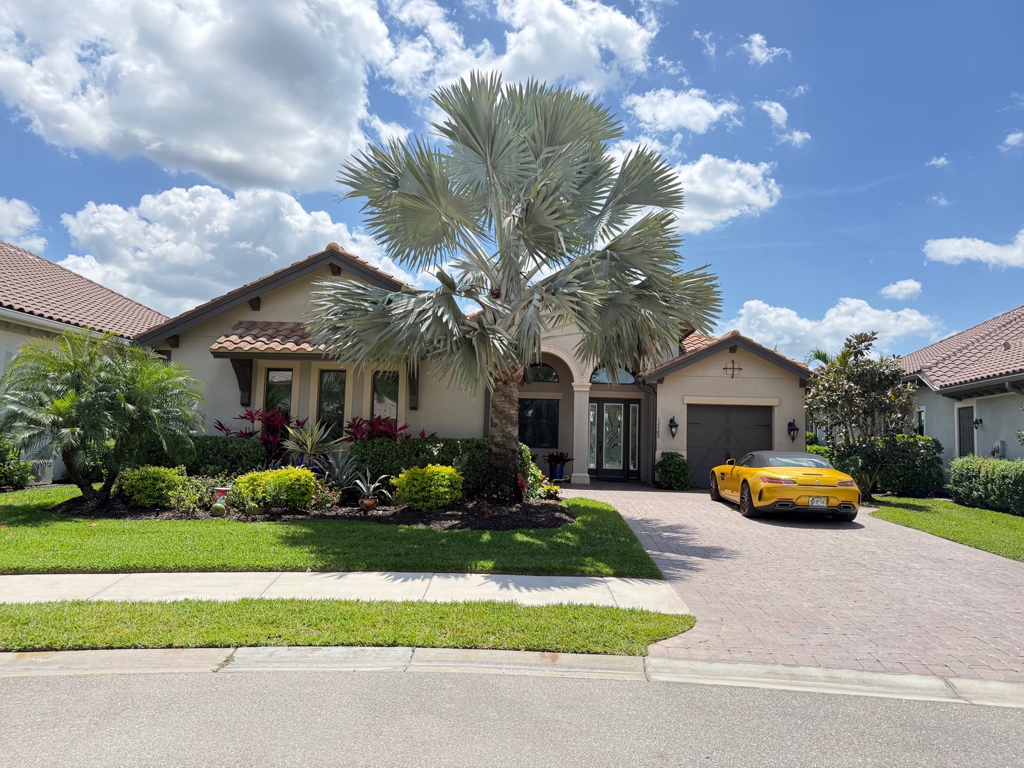 Beautiful Mediterranean-style vacation home with landscaped gardens and convenient driveway parking in a peaceful residential neighborhood.