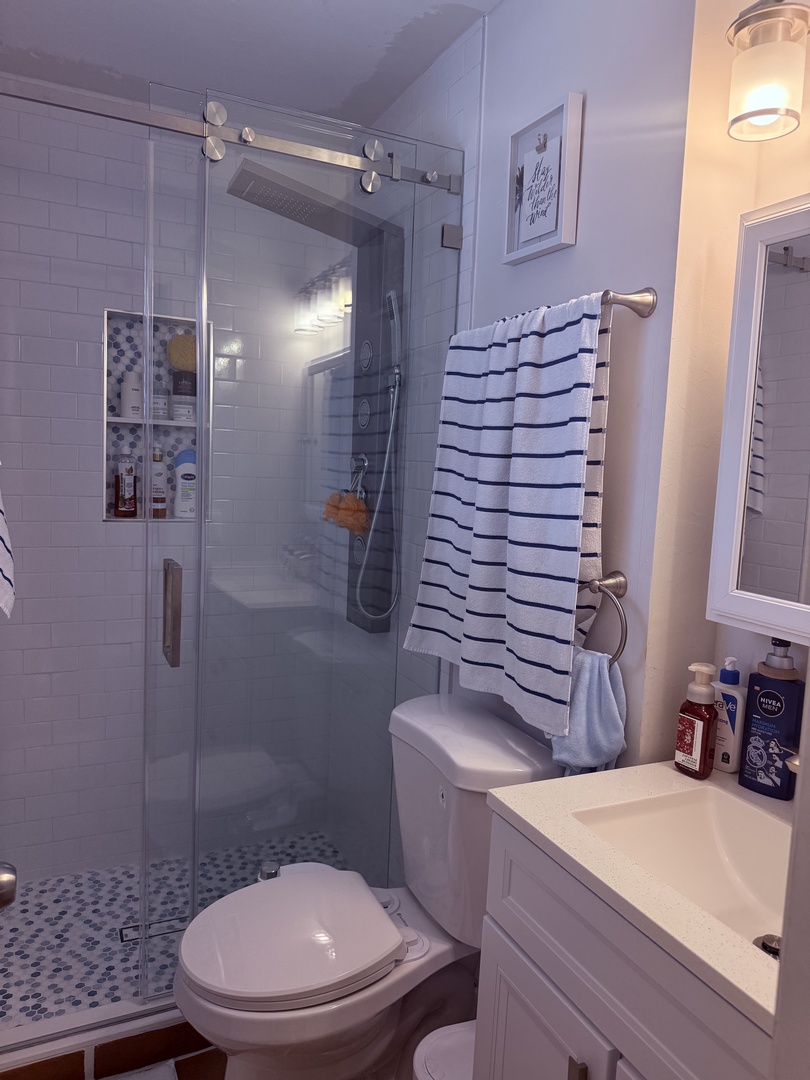 Your private bathroom combines classic elegance with modern comfort—fresh white subway tiles, a spacious glass-enclosed shower, and plush linens await your arrival.