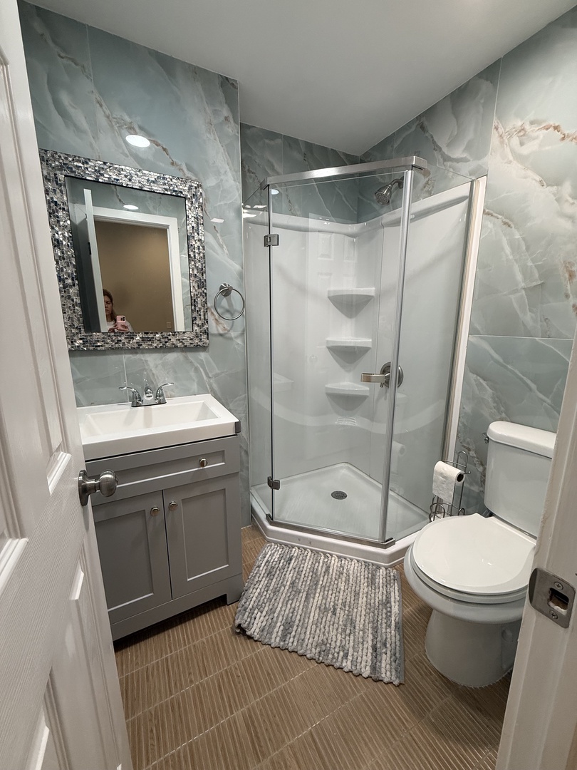 Step into your private spa-inspired first floor/pool accessible bathroom with elegant marble-like walls, a sleek glass-enclosed shower, and plush towels waiting for you.