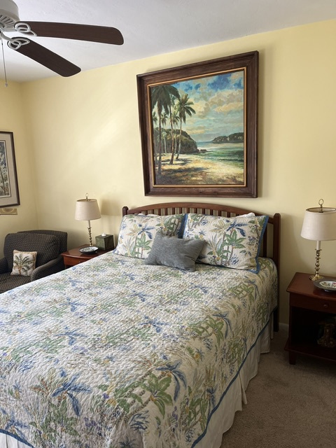 Sink into crisp tropical linens and let the ceiling fan's gentle breeze lull you into a peaceful rest in your coastal-themed bedroom.