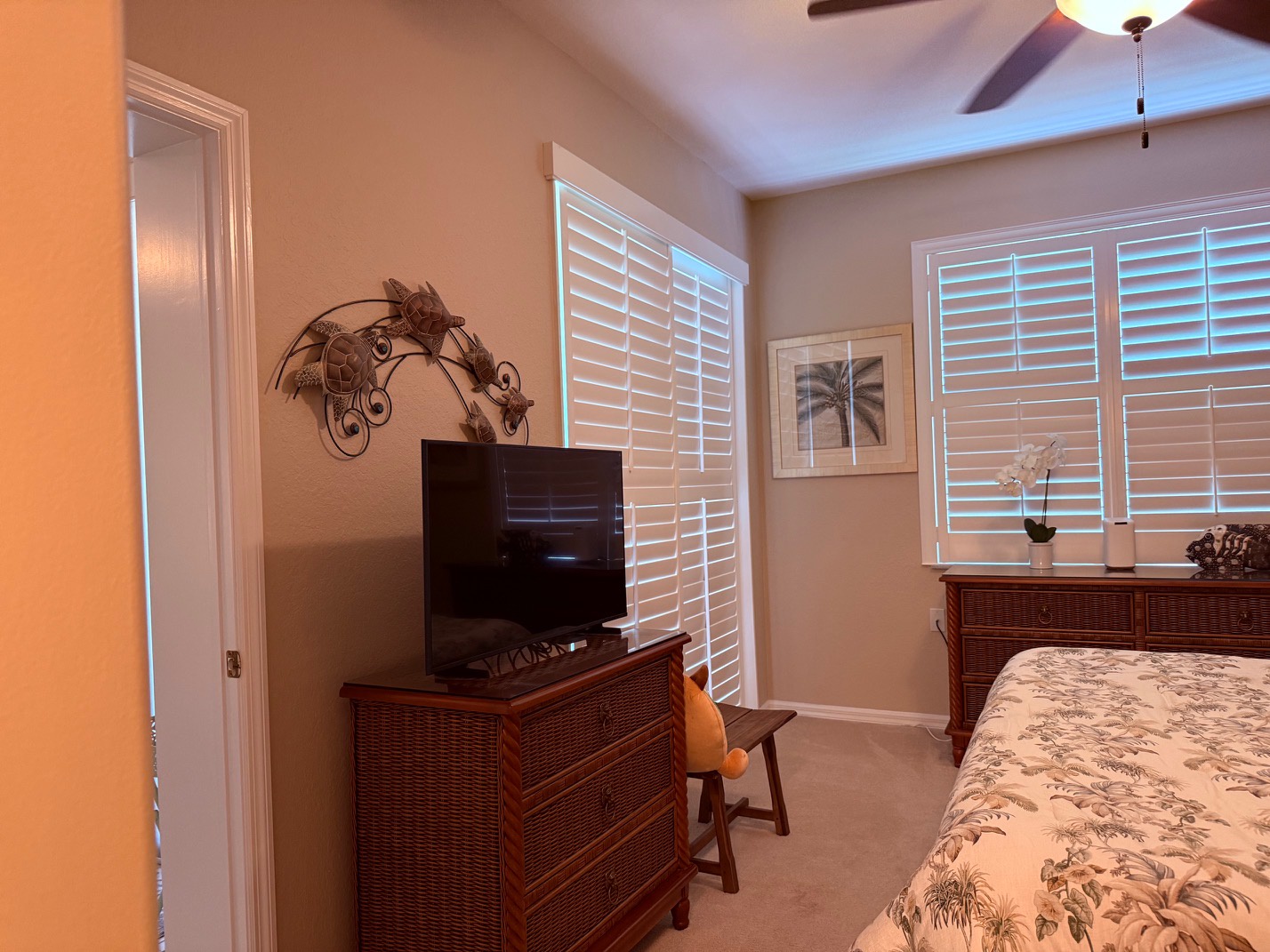Bedroom 1 King  with TV Your peaceful bedroom retreat features warm coastal tones, tropical accents, and gentle natural light filtering through plantation shutters. Relax with all the comforts of home in this inviting space.