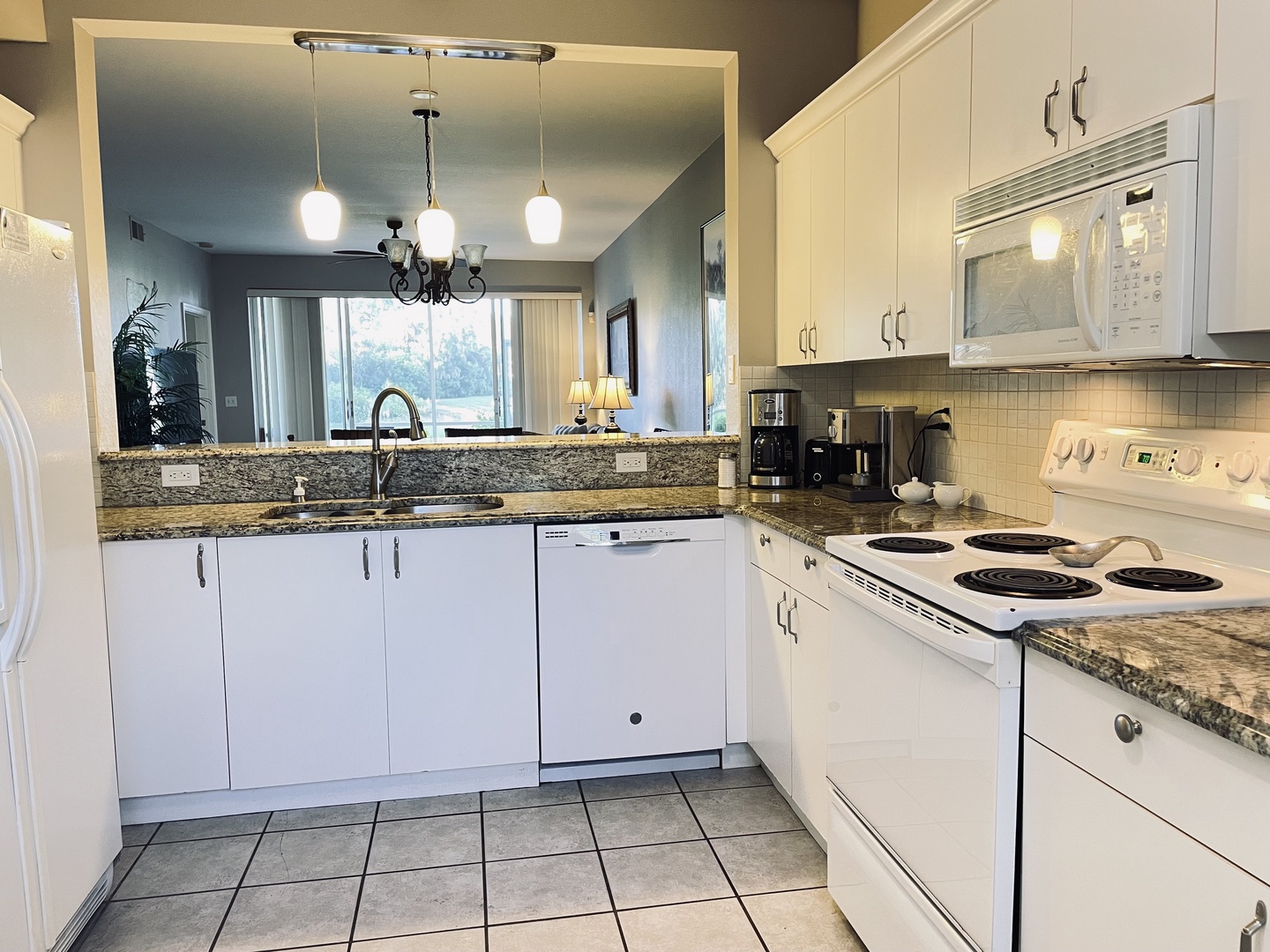 Cook your favorite meals in this spacious kitchen featuring granite countertops, full appliances, and an open layout perfect for vacation dining.