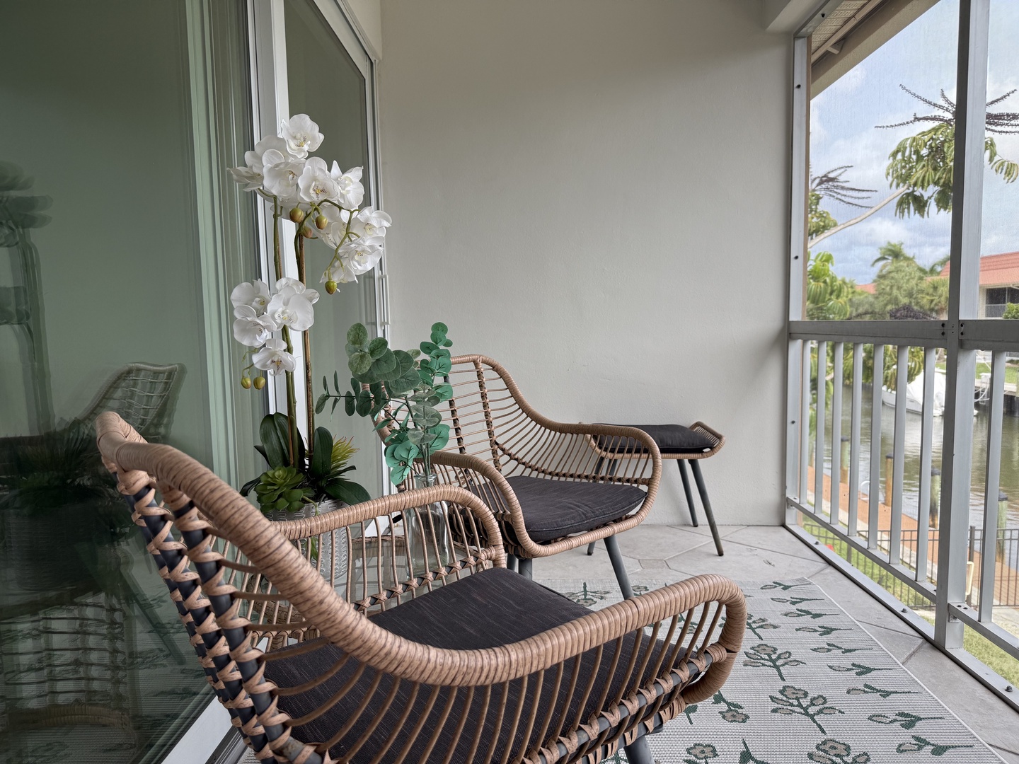 Sink into stylish rattan seating on your private balcony, where elegant orchids frame tropical palm views and gentle breezes invite peaceful moments.
