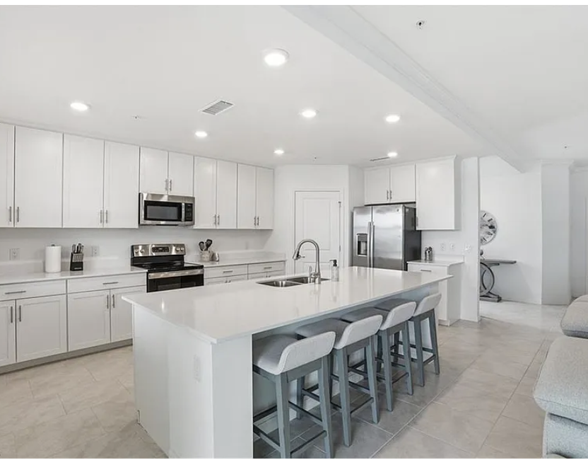 Your gourmet kitchen awaits with gleaming white quartz countertops, stainless steel appliances, and a spacious island perfect for gathering and meal prep.