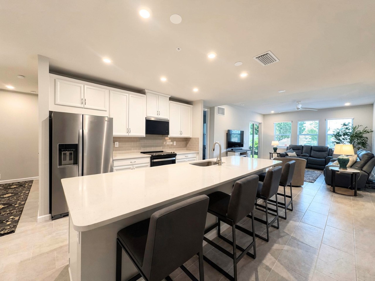 Stunning kitchen island with seating for four, sleek white countertops, and modern appliances. Open layout flows seamlessly into the bright living area—perfect for meal prep and gathering.