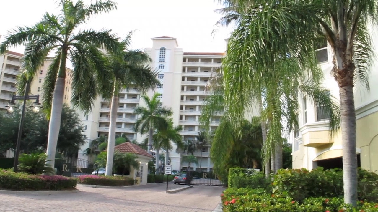 Multi-story resort buildings surrounded by lush palm trees and tropical landscaping create an elegant tropical setting.