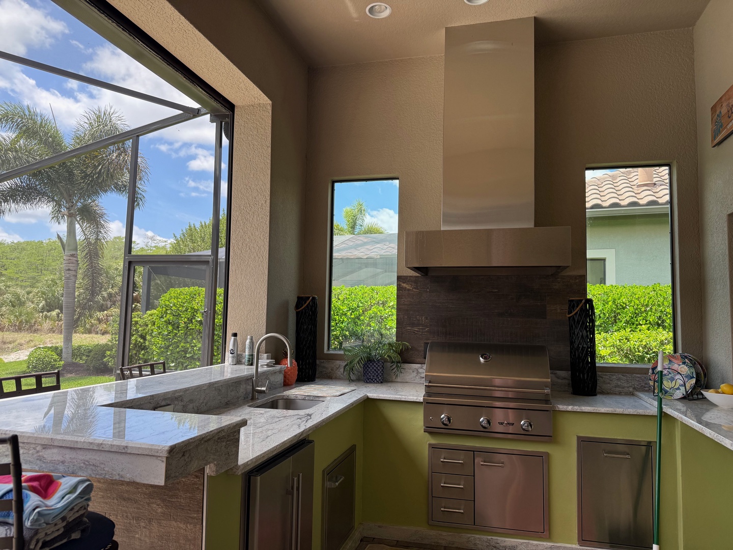 Your outdoor kitchen offers premium grilling with stunning garden views through floor-to-ceiling windows, perfect for memorable cooking experiences.
