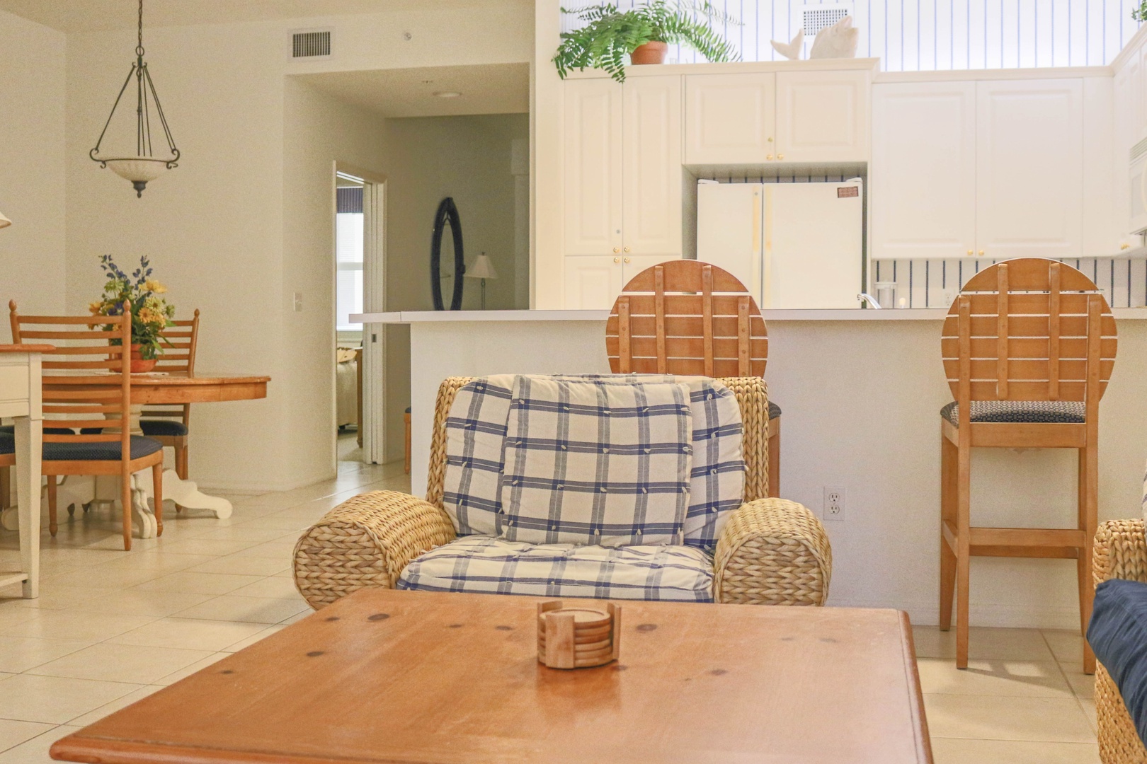Relax in your bright, airy living space with comfortable wicker seating and an open layout that flows seamlessly into the kitchen.