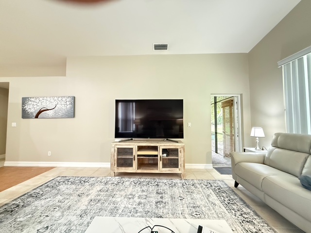 Relax in your bright living room with plush seating, modern TV, and peaceful patio access for quiet moments.