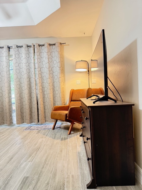 Unwind in your stylish retreat featuring a cozy orange armchair, modern workspace, and warm lighting that creates the perfect atmosphere for relaxation.