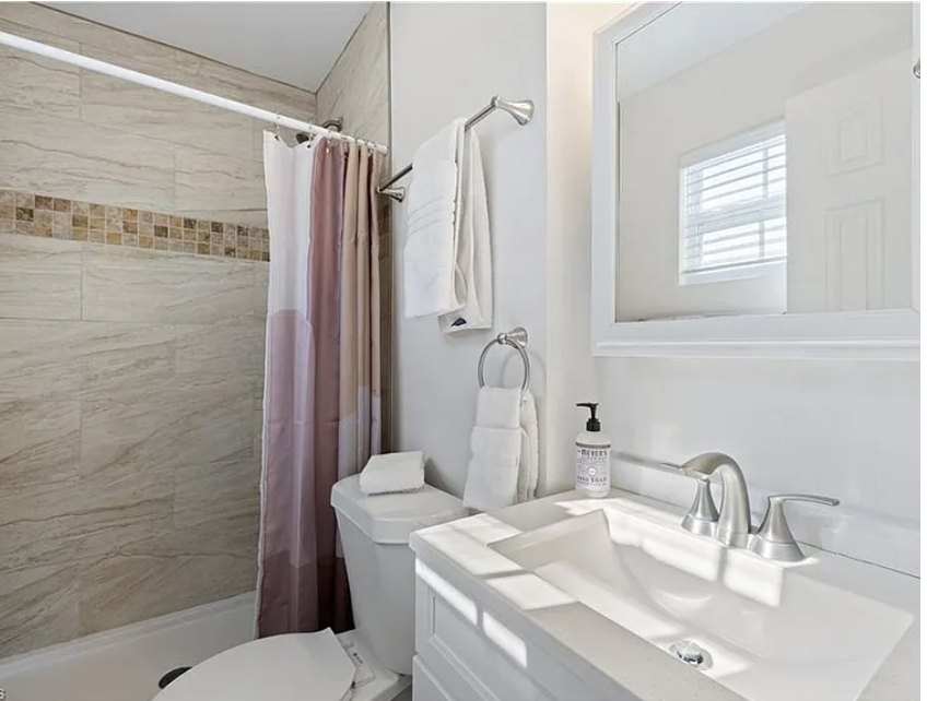 Step into your private bathroom with elegant tile work, soft linens, and natural light from the window. The tub-shower combo and sleek vanity make freshening up a breeze.
