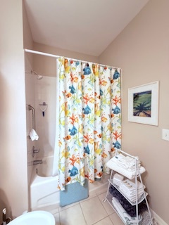 Step into your sparkling clean bathroom, complete with a tub-shower combo and cheerful curtain. Soft towels await you on the convenient storage rack.