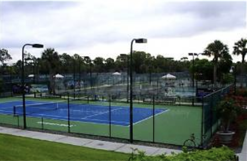 The property features multiple well-maintained tennis courts surrounded by tropical landscaping and palm trees, perfect for active travelers looking to enjoy outdoor recreation.