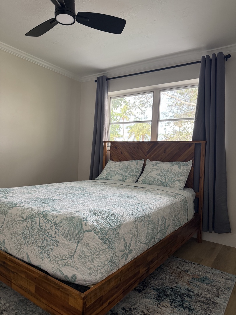 Your bright bedroom features quality bedding and peaceful garden views through large windows, with a ceiling fan ensuring comfort.