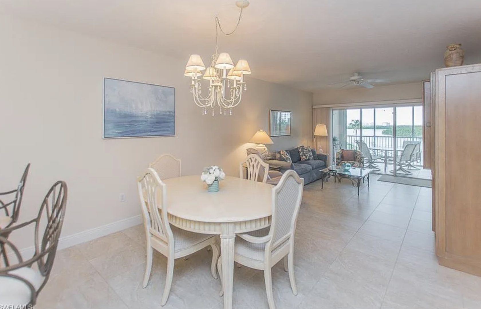 Open-concept living and dining area with soft coastal tones and elegant lighting. Gather for meals, then unwind in the cozy living space with private balcony access.