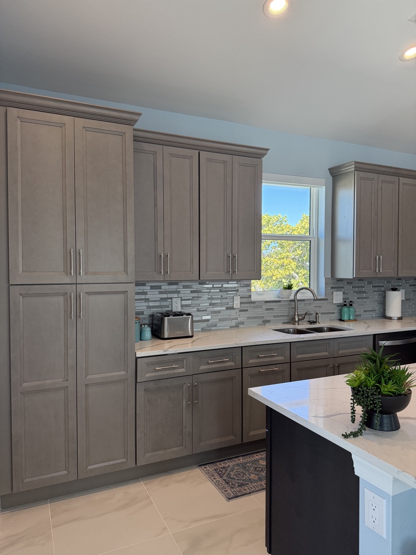 Cook your favorite meals in this fully-equipped kitchen featuring sleek gray cabinets, modern appliances, and plenty of counter space for prep work.