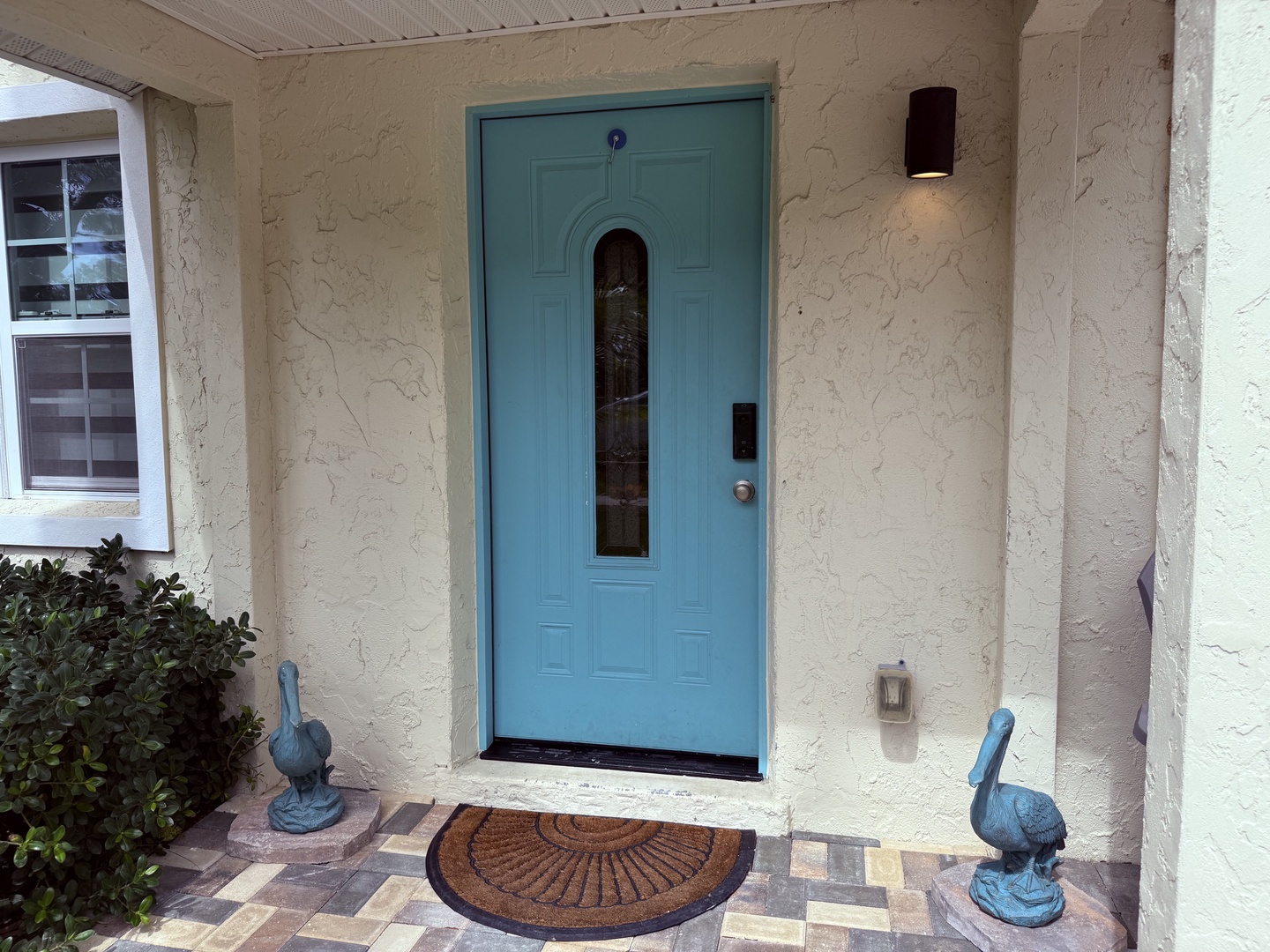 The charming turquoise door and decorative heron statues welcome you to your coastal retreat, offering a bright and inviting first impression the moment you arrive.