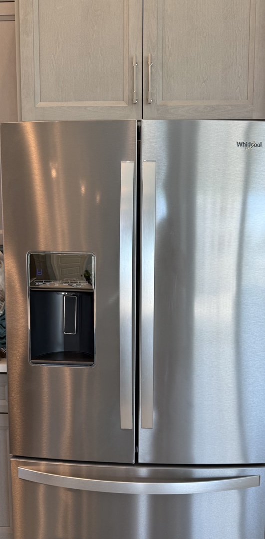 Your spacious kitchen features a premium stainless steel refrigerator with convenient water and ice dispenser, perfectly matched with elegant cabinetry.