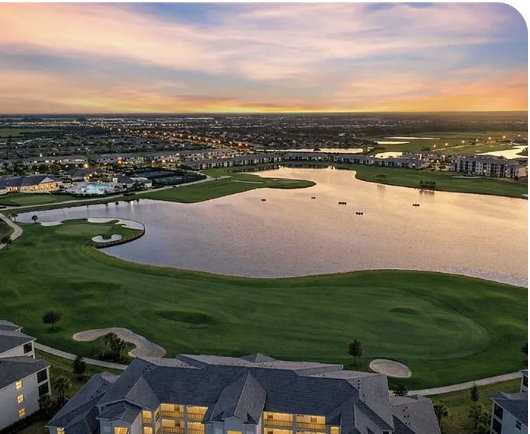 Aerial view of the property showcasing a stunning waterfront golf course and surrounding residential community at sunset.