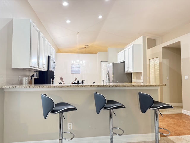 Your modern kitchen features sleek white cabinets, granite countertops, and a breakfast bar where you can enjoy morning coffee.