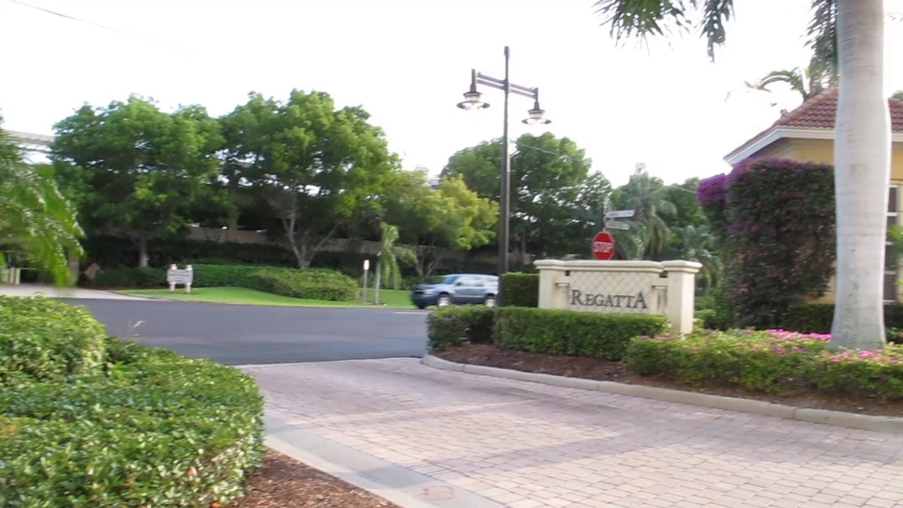 The elegant Regatta entrance welcomes guests with manicured landscaping and tropical charm in this peaceful residential setting.