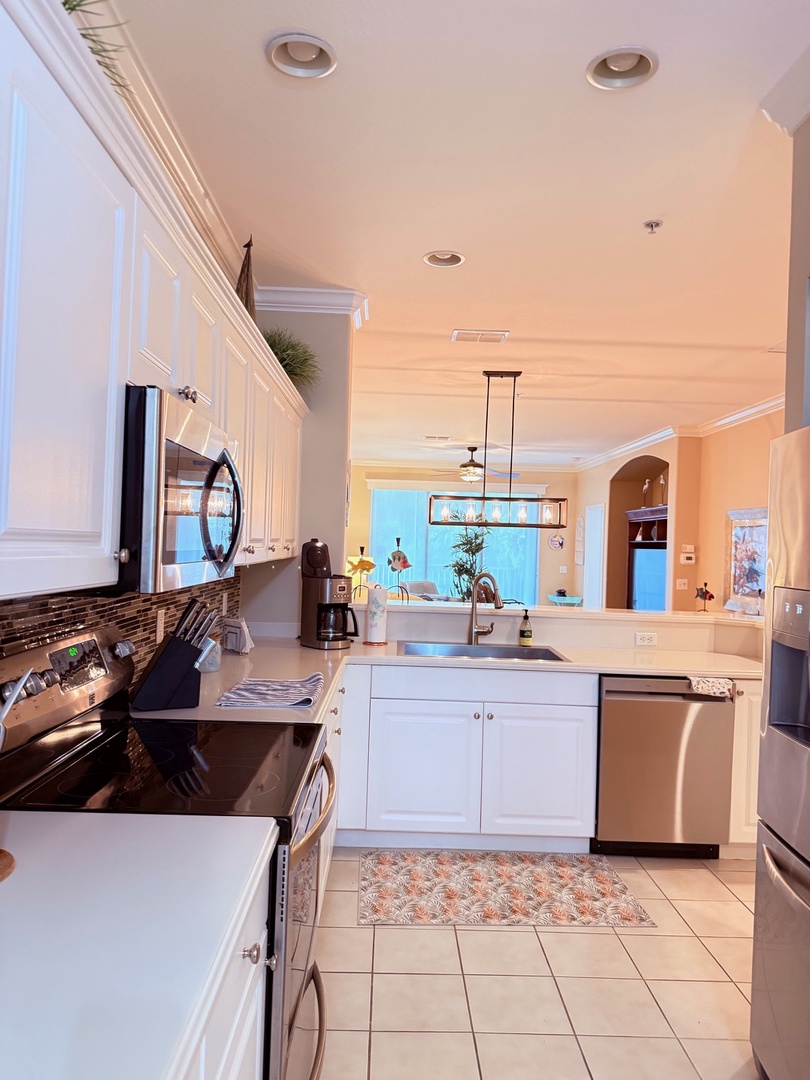 Your fully equipped kitchen opens to an inviting space with views of the pool area, making meal prep feel like part of your vacation.