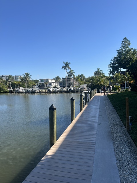 A serene waterfront community with private dock access under sunny Florida skies, surrounded by tropical landscaping and modern residences.