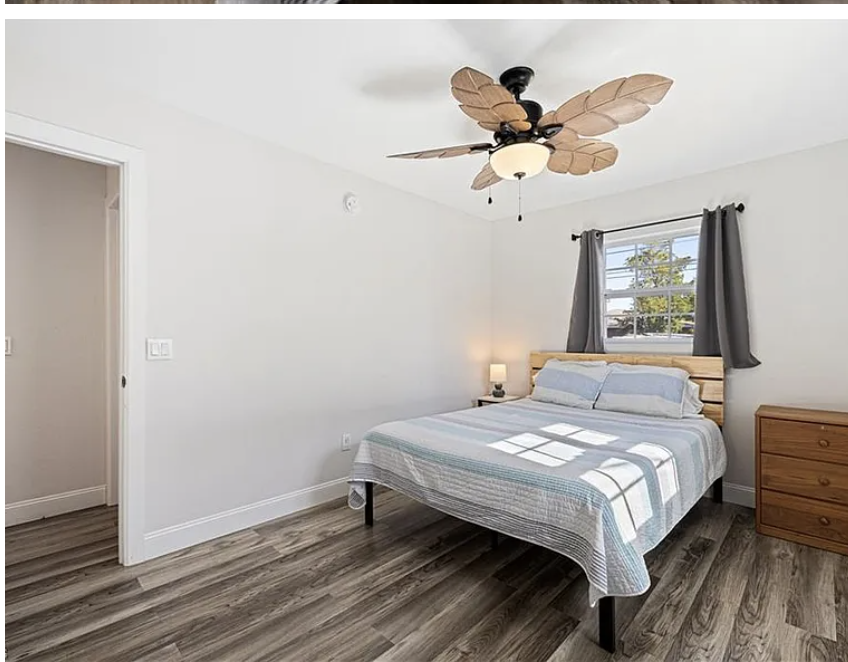 Drift off in this bright, airy bedroom where sunlight streams through the window and a tropical-inspired ceiling fan keeps you cool. Your peaceful retreat awaits.