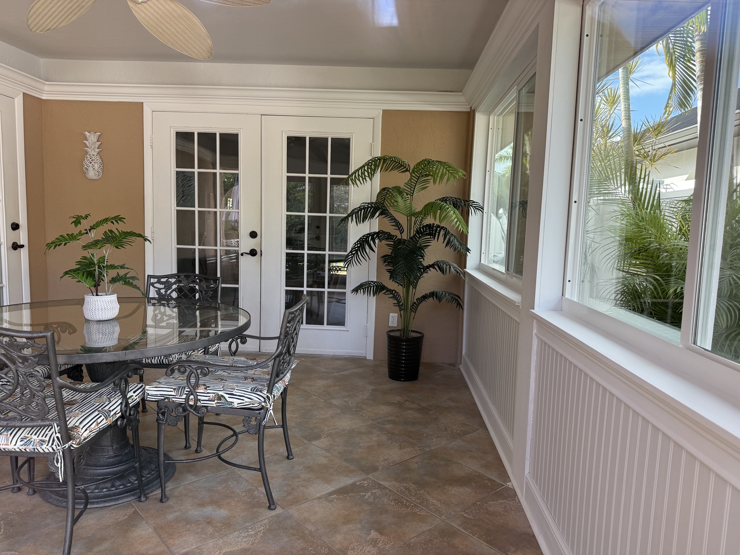 Your enclosed Florida sunroom patio offers elegant dining with tropical palm views through oversized windows, creating a bright, breezy retreat.