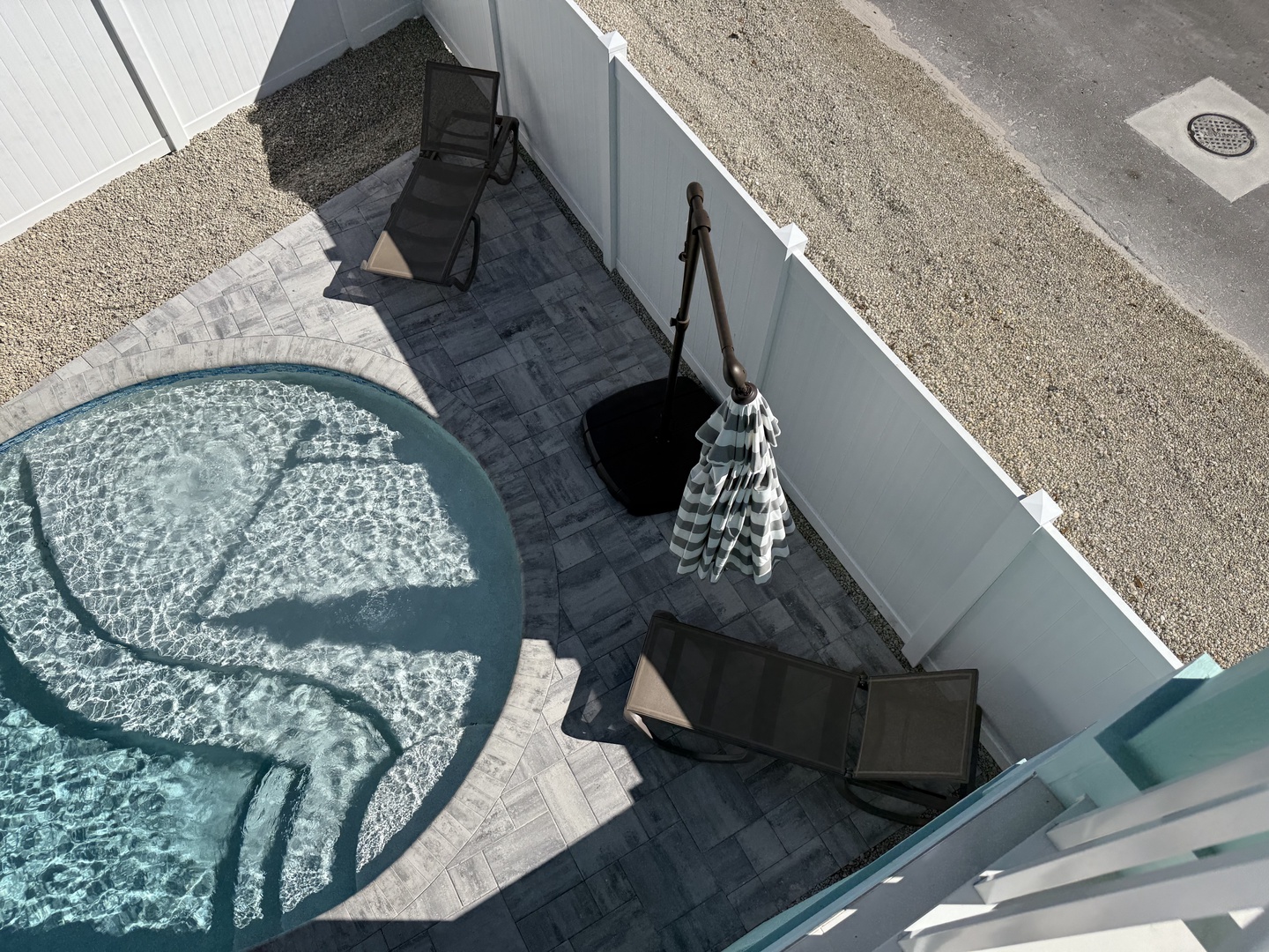 Aerial view of the property's outdoor pool area and patio with seating and umbrella for shade.