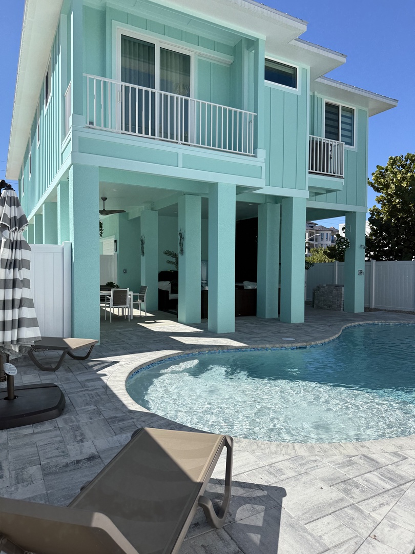 Modern turquoise villa with sparkling pool and spacious terrace area surrounded by clean contemporary architecture.