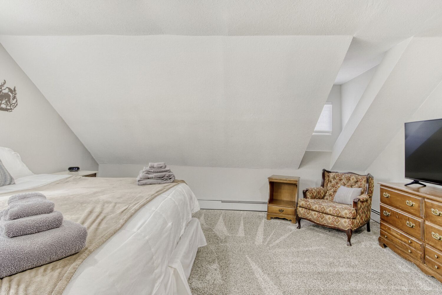Relax in your peaceful attic retreat with cozy sloped ceilings, plush towels, and charming vintage touches.