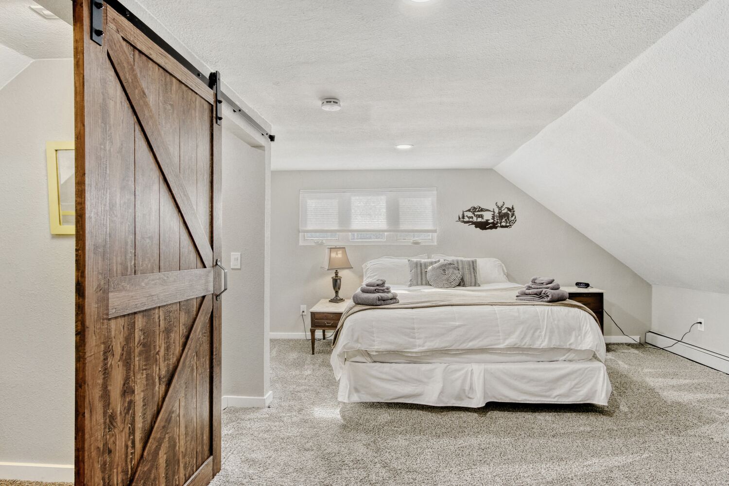 Your peaceful retreat awaits in this cozy primary bedroom with ensuite bathroom, complete with rustic barn door charm and plush linens for the perfect night's rest.