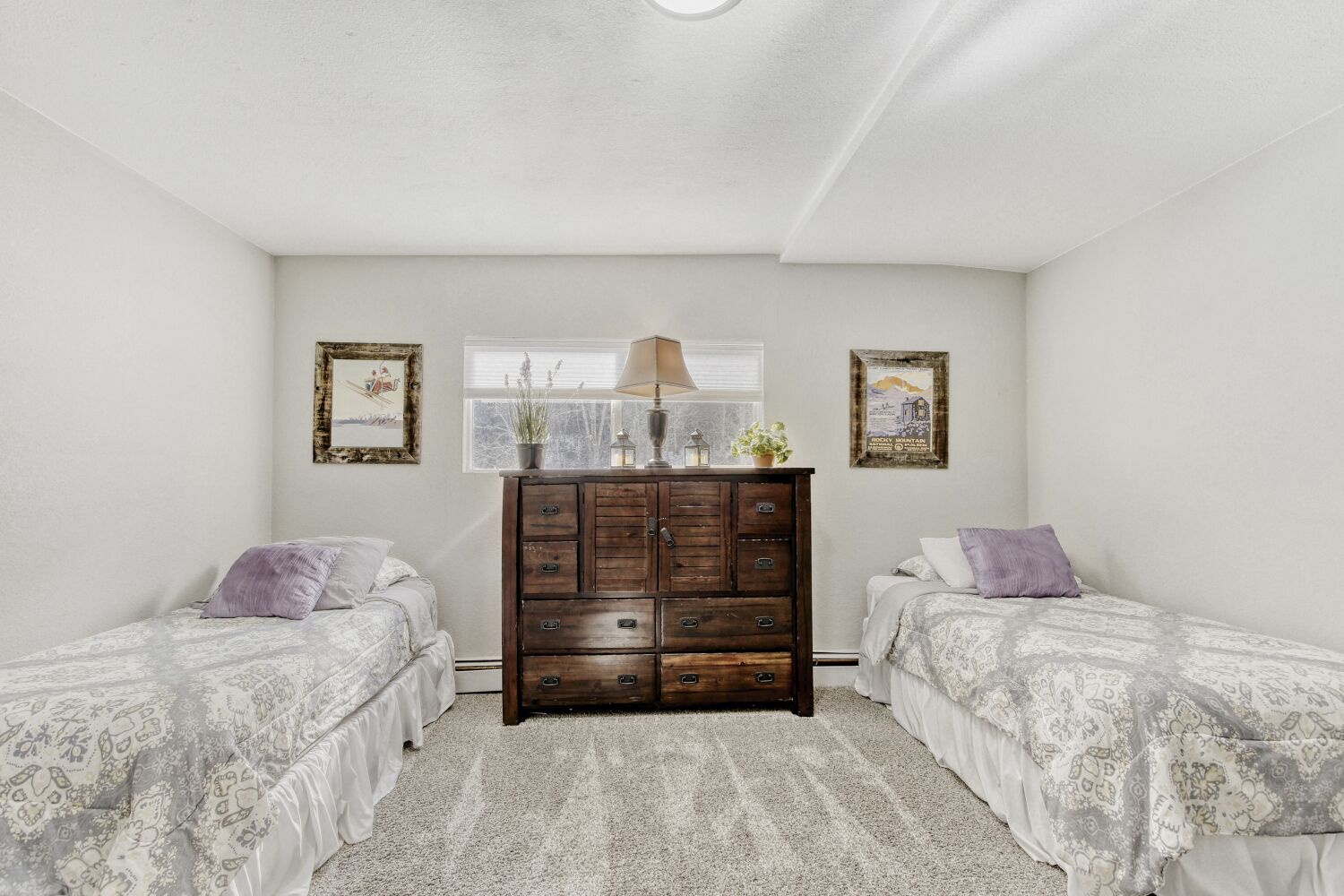 Relax in this peaceful twin bedroom with comfortable beds, charming rustic dresser, and natural light from the garden window.