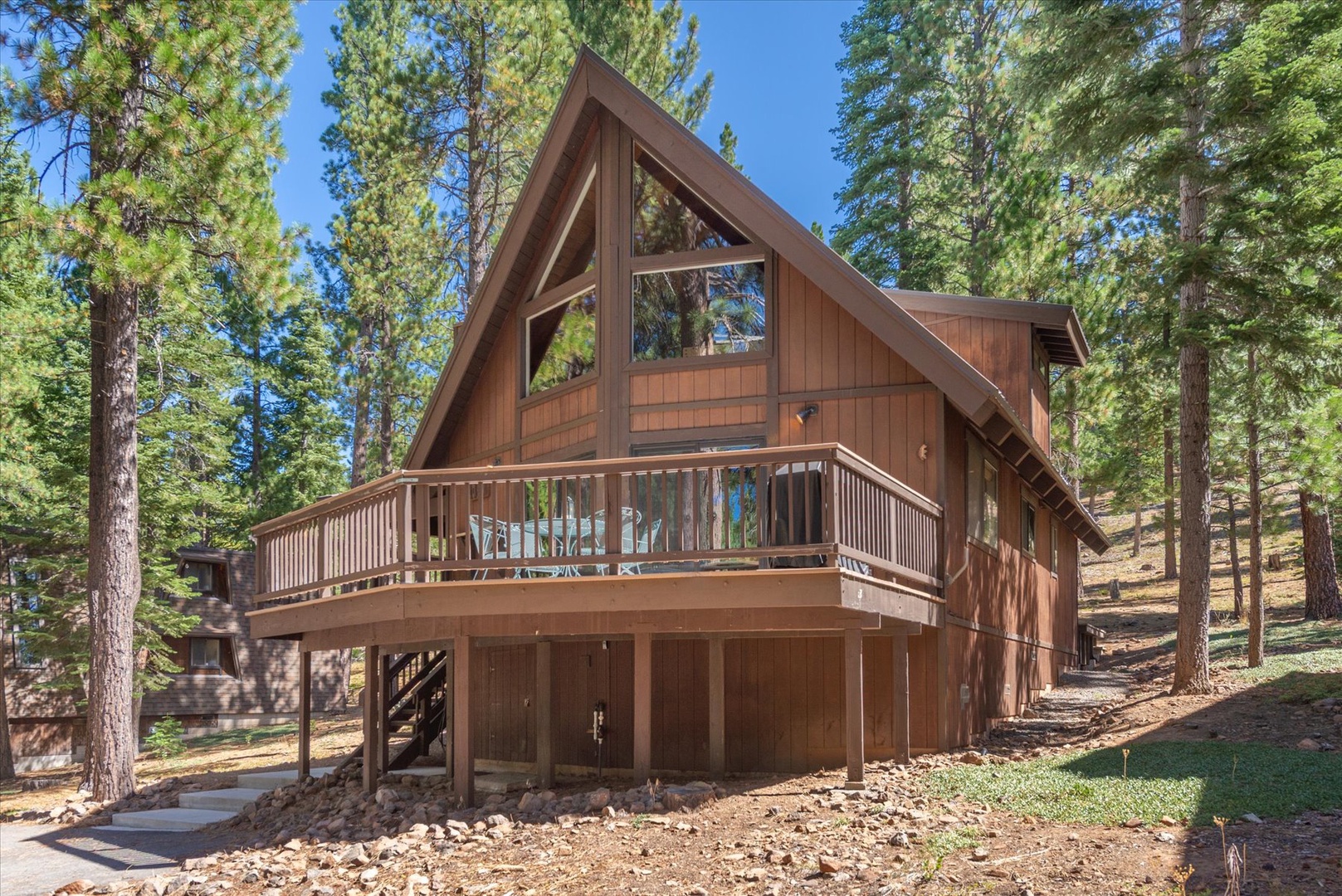 A charming Tahoe A-frame cabin nestled among towering pines, featuring warm wood tones and a spacious deck for soaking in the natural surroundings.