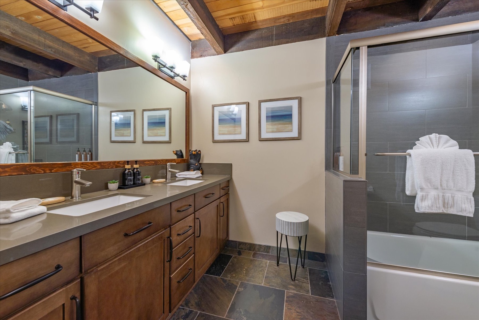 Unwind in your spa-like bathroom with rustic beams overhead, sleek stone finishes, and plush towels ready for your mountain retreat.