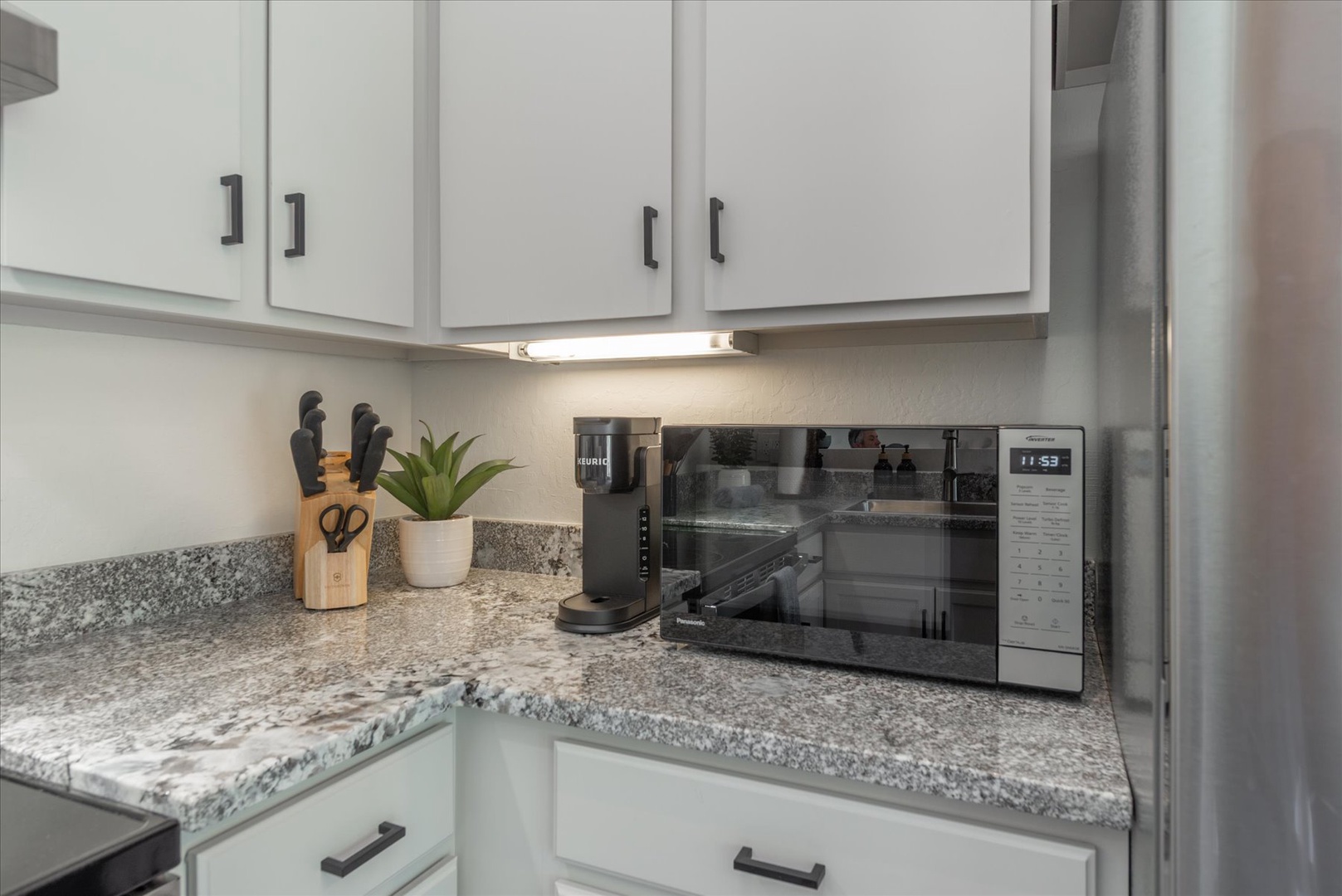 Your fully equipped kitchen awaits, featuring sleek granite countertops, modern appliances including a microwave, and ample cabinet space for your culinary adventures.