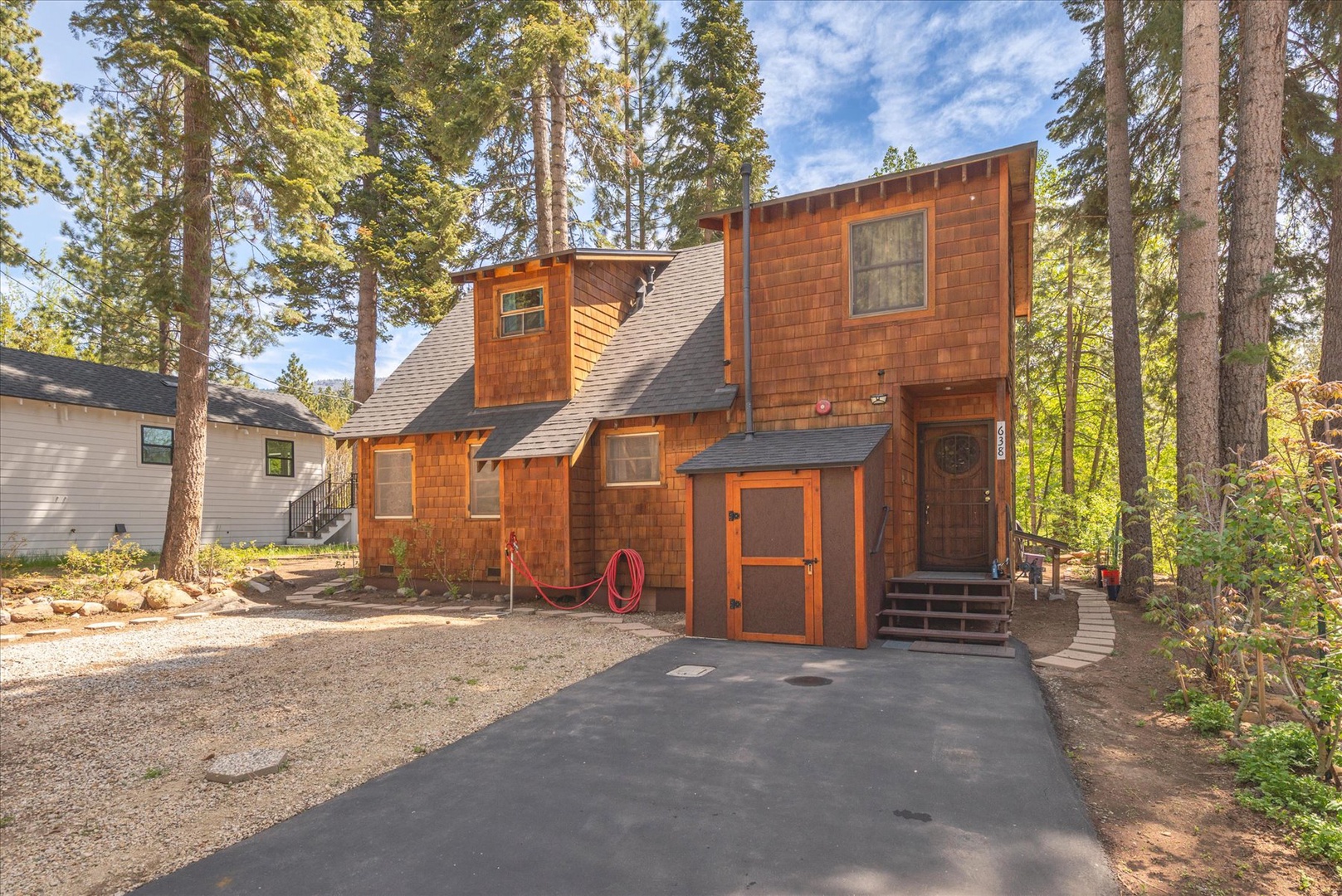 Charming wood-shingled cabin nestled among towering pines with private driveway and wooded setting for peaceful mountain retreat.